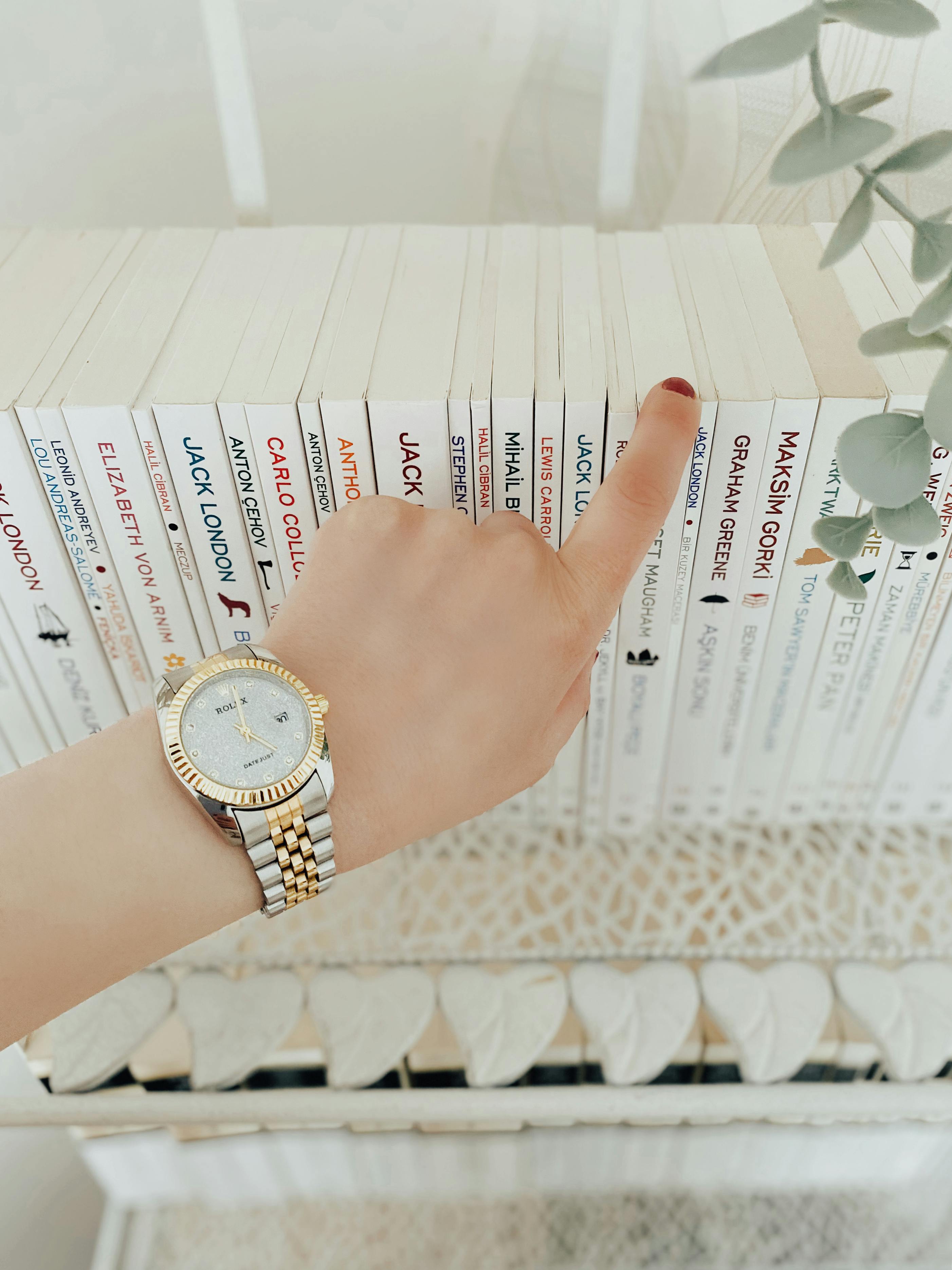 person with watch pointing on books