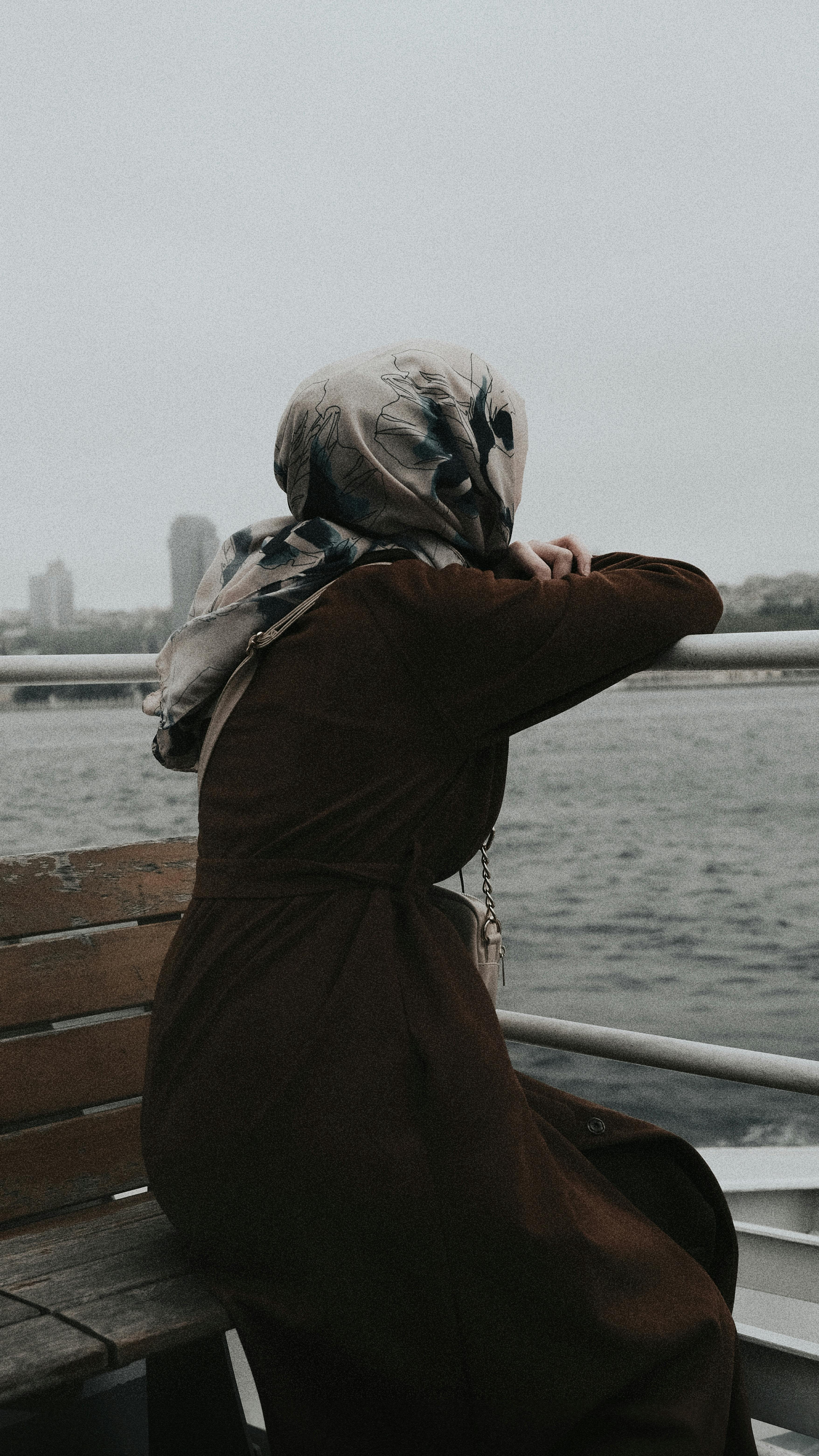 A serene moment captured of a woman in a headscarf gazing over the water towards Istanbul.