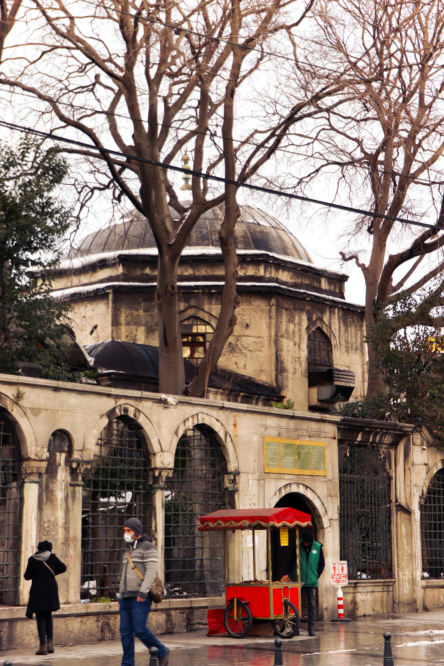 Street scene in Istanbul with an ancient mosque and a traditional street vendor cart.