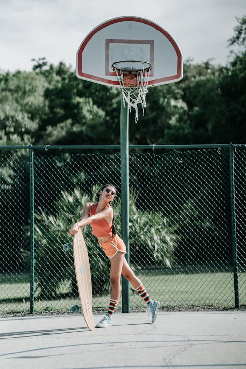 Free Woman in Red and White Jersey Shirt and Shorts Playing Basketball Stock Photo