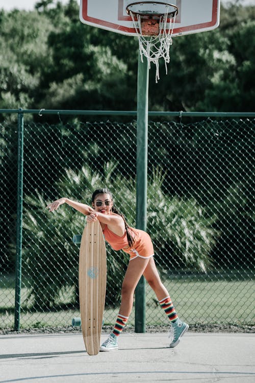 Free Woman in Orange Sports Bra and Shorts Holding Tennis Racket Stock Photo