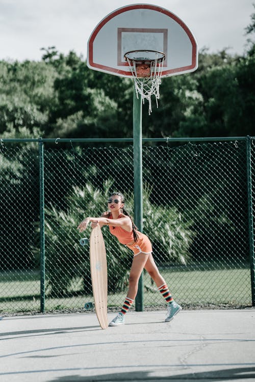 Free Woman in Orange Jersey Shirt and White Shorts Playing Basketball Stock Photo