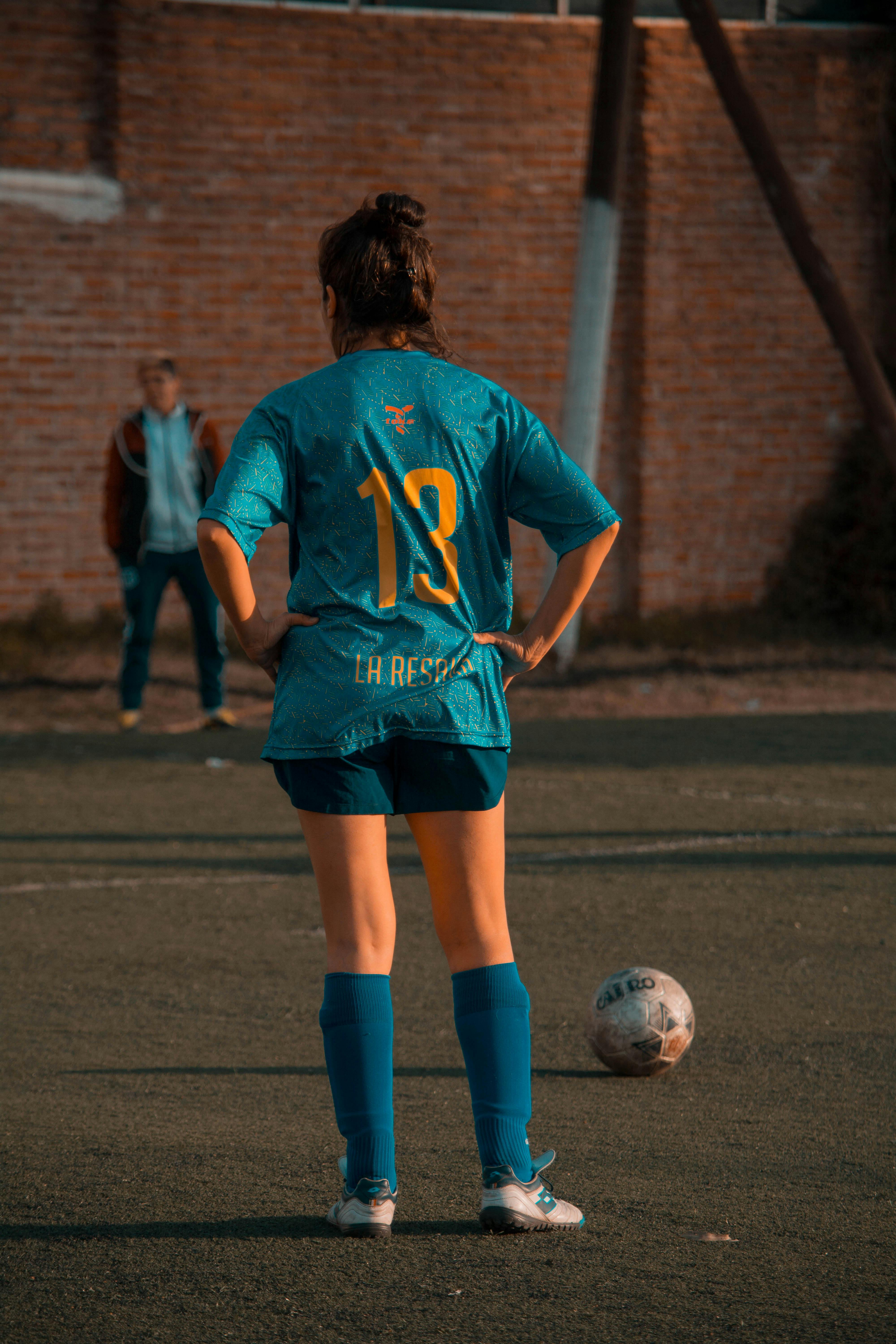 person in blue soccer jersey standing in front of ball