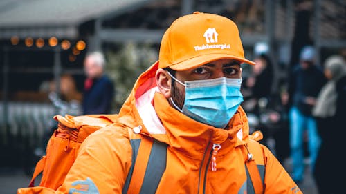 Free A Man in Orange Uniform Wearing Face Mask while Looking at the Camera Stock Photo