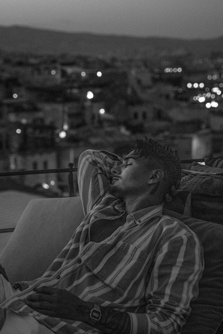 Grayscale Photo Of Man In Stripe Long Sleeves Sitting On A Couch 