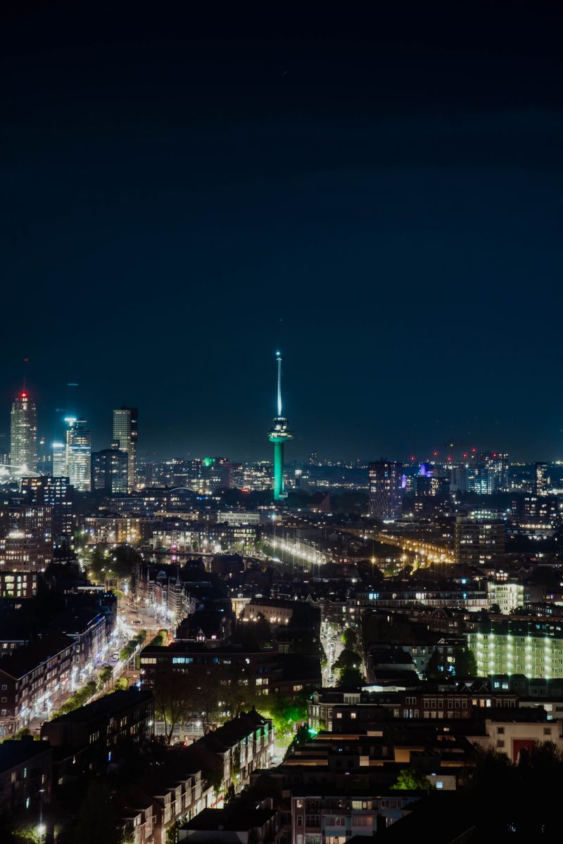 Aerial view of Rotterdam's illuminated skyline featuring the iconic Euromast at night.