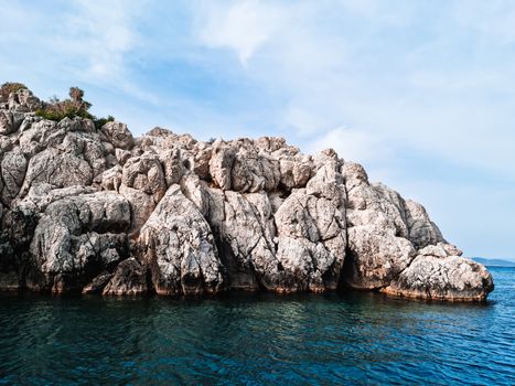 Majestic rock formations emerging from the azure Aegean Sea under a bright sky in Chios, Greece.