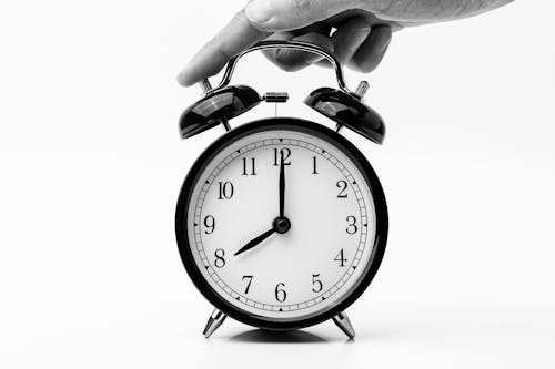 Person Touching Black Two-bell Alarm Clock