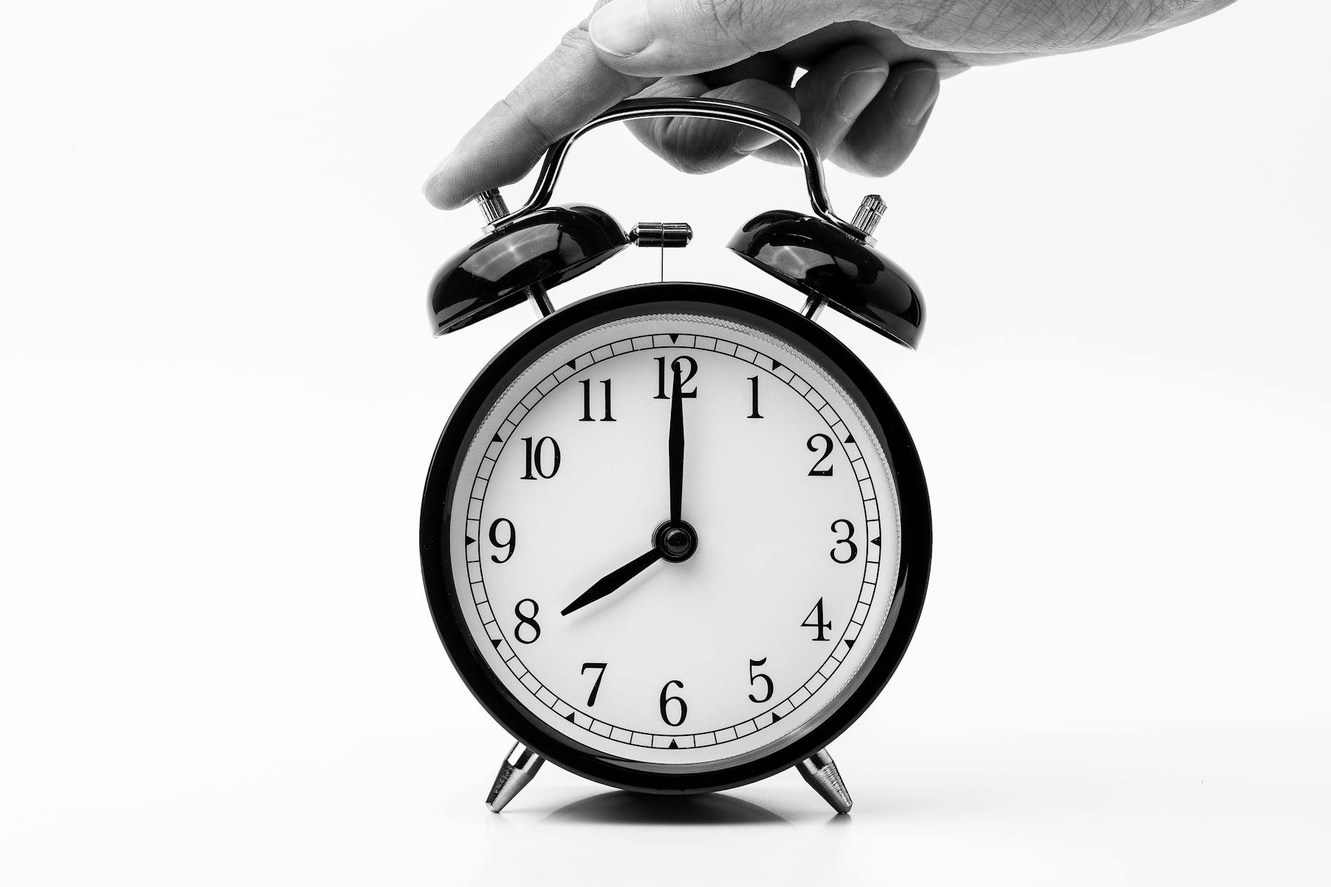 Person Touching Black Two-bell Alarm Clock