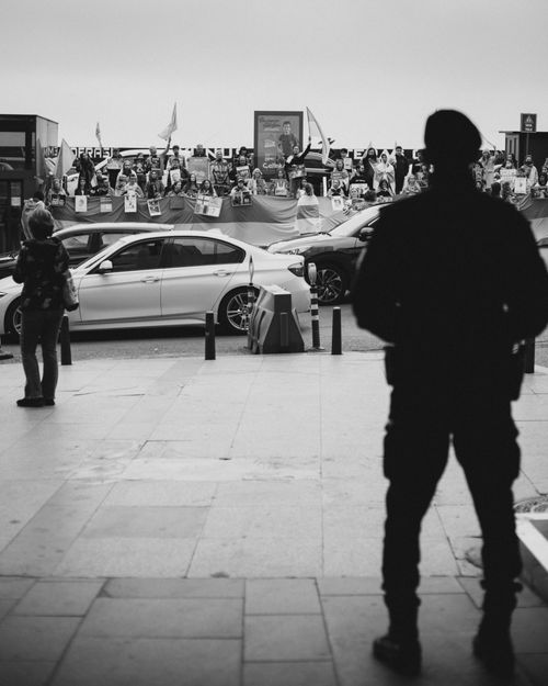 Free Black and white photo of a silhouette security officer observing a public protest. Stock Photo