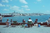 Man in Green Shirt Sitting on Chair Near Body of Water