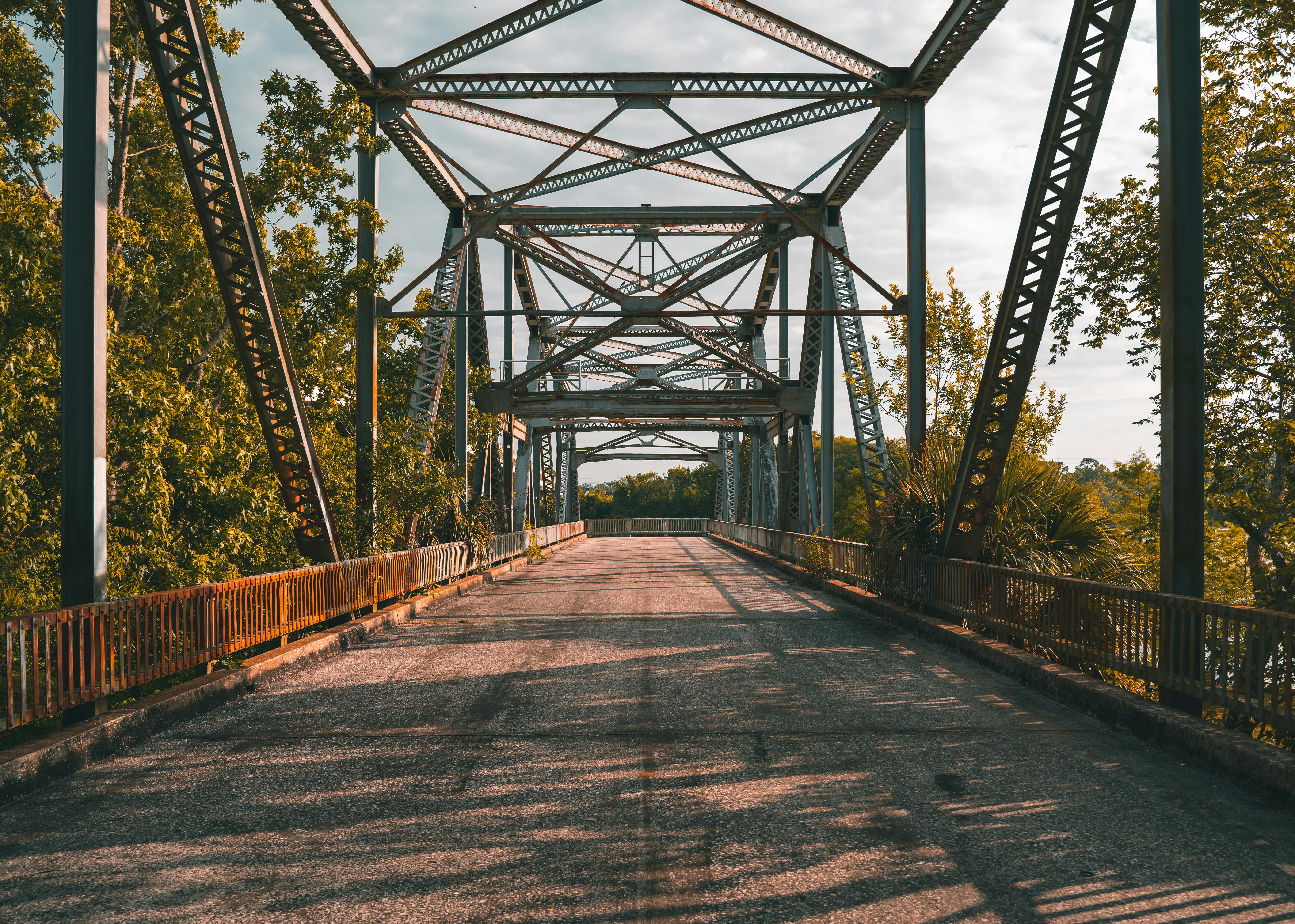Explore the timeless beauty of an empty steel truss bridge surrounded by lush greenery in Sanford, Florida.