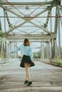 Woman in Blue Long Sleeve Shirt and Black Skirt Walking on Gray Concrete Road
