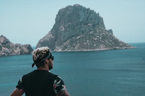 Man Looking at Mountain Across Ocean
