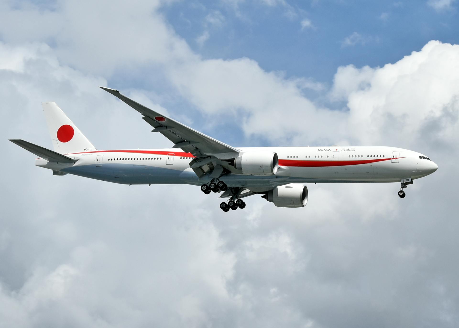 A Japanese Boeing 777 aircraft in mid-air against a backdrop of clouds, showcasing aviation elegance.