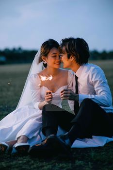 Bride and groom sharing a romantic moment with sparklers outdoors in Vietnam.
