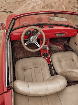 High angle shot of a classic red convertible car's interior with beige seats.