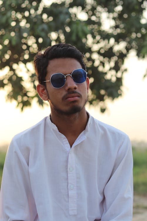 Man Wearing a White Button Down Shirt and Sunglasses Posing