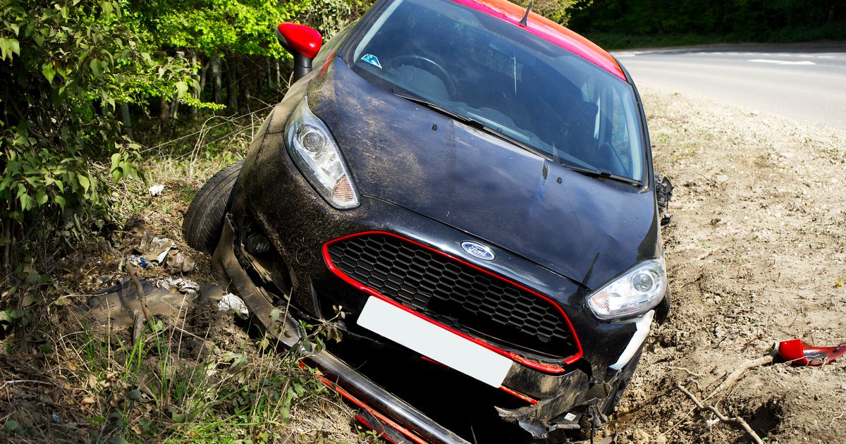 Win No Fee Solicitors: How No Win No Fee Works for UK Injury Claims — A black car, seemingly a Ford, crashed and damaged in a roadside ditch with surrounding greenery.