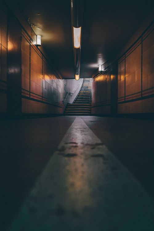 Free A dimly lit underground tunnel in London leading to stairs, creating a moody atmosphere. Stock Photo