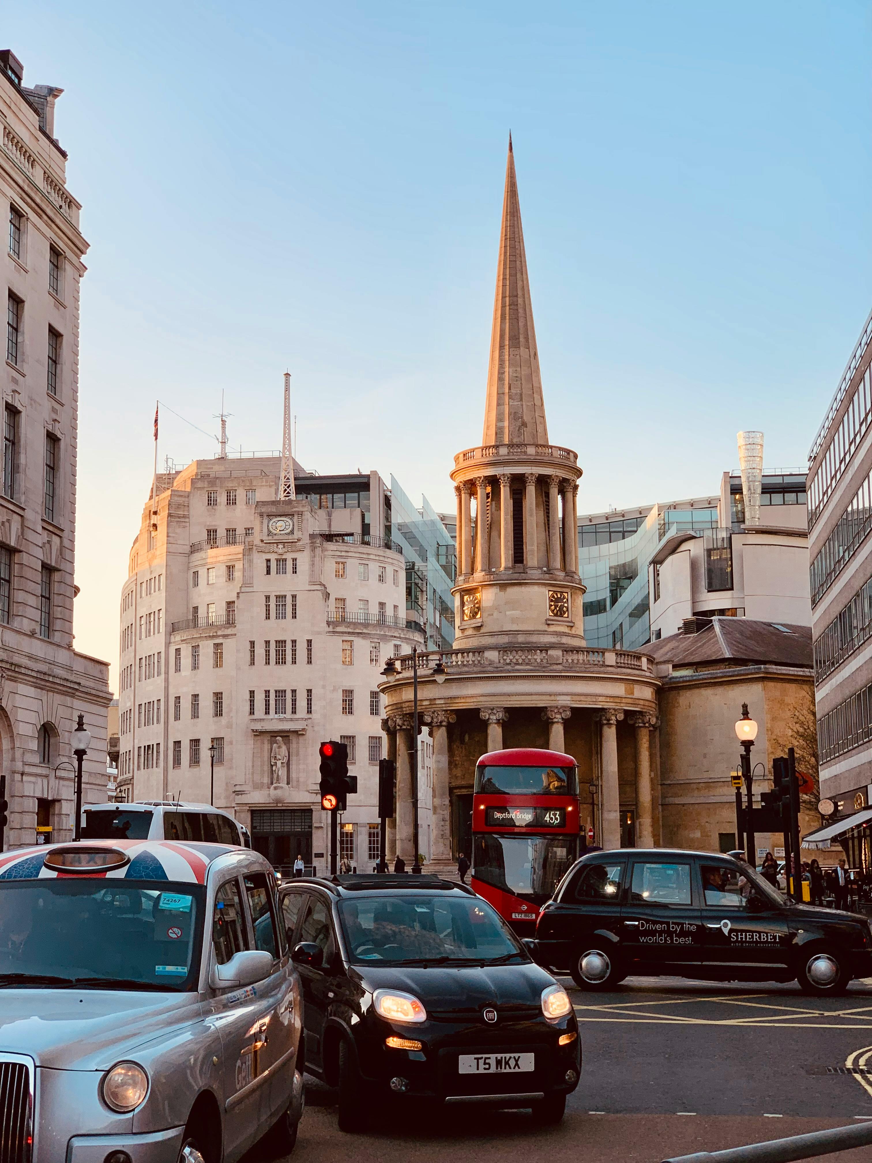 View of London street with iconic red bus, taxis, and All Souls Church captured at sunset.