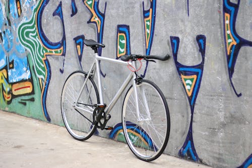 Black and Silver Road Bike Leaning on Wall With Graffiti