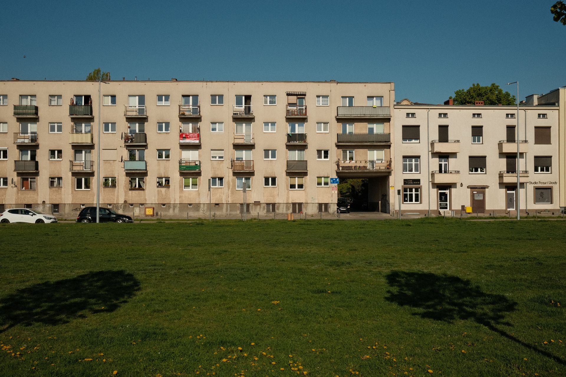 Exterior view of an urban apartment complex with green lawn and balconies.