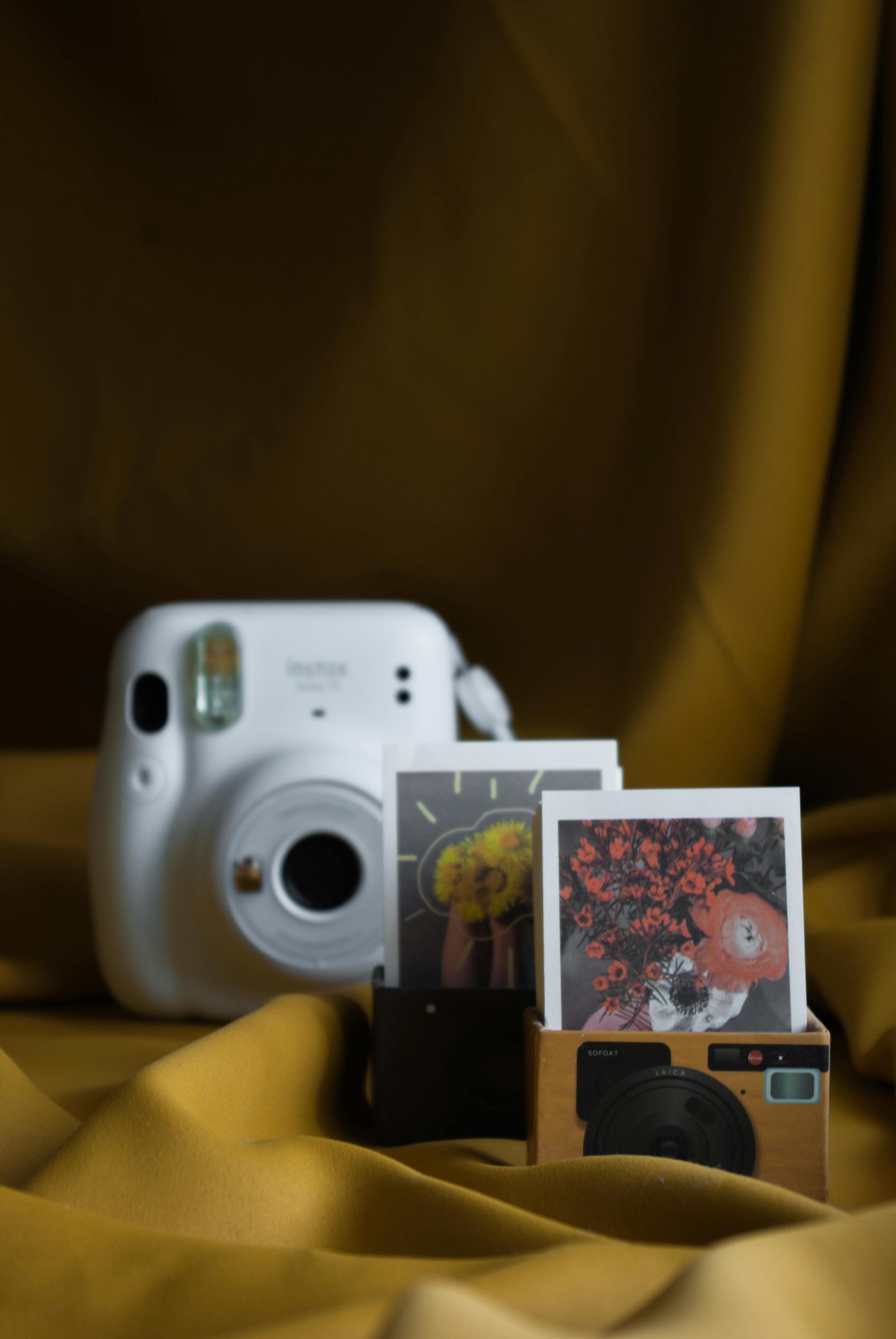 A white instant camera next to colorful polaroid prints on a yellow background.