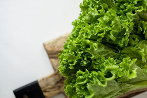 Free Close-up of fresh green lettuce leaves on a rustic wooden cutting board. Stock Photo
