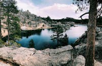 南达科他州卡斯特州立公园内，宁静的湖泊被岩石山丘和针叶树环绕