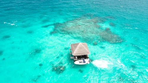 無料 パワーボートの横にある水域の茶色の家の航空写真 写真素材
