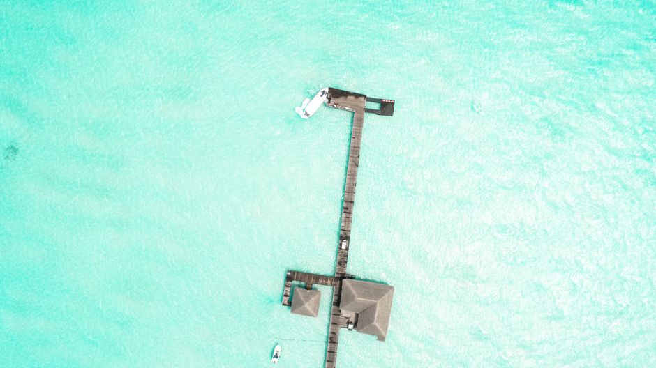 Stunning aerial view of a dock over clear turquoise waters in Kaafu Atoll, Maldives.