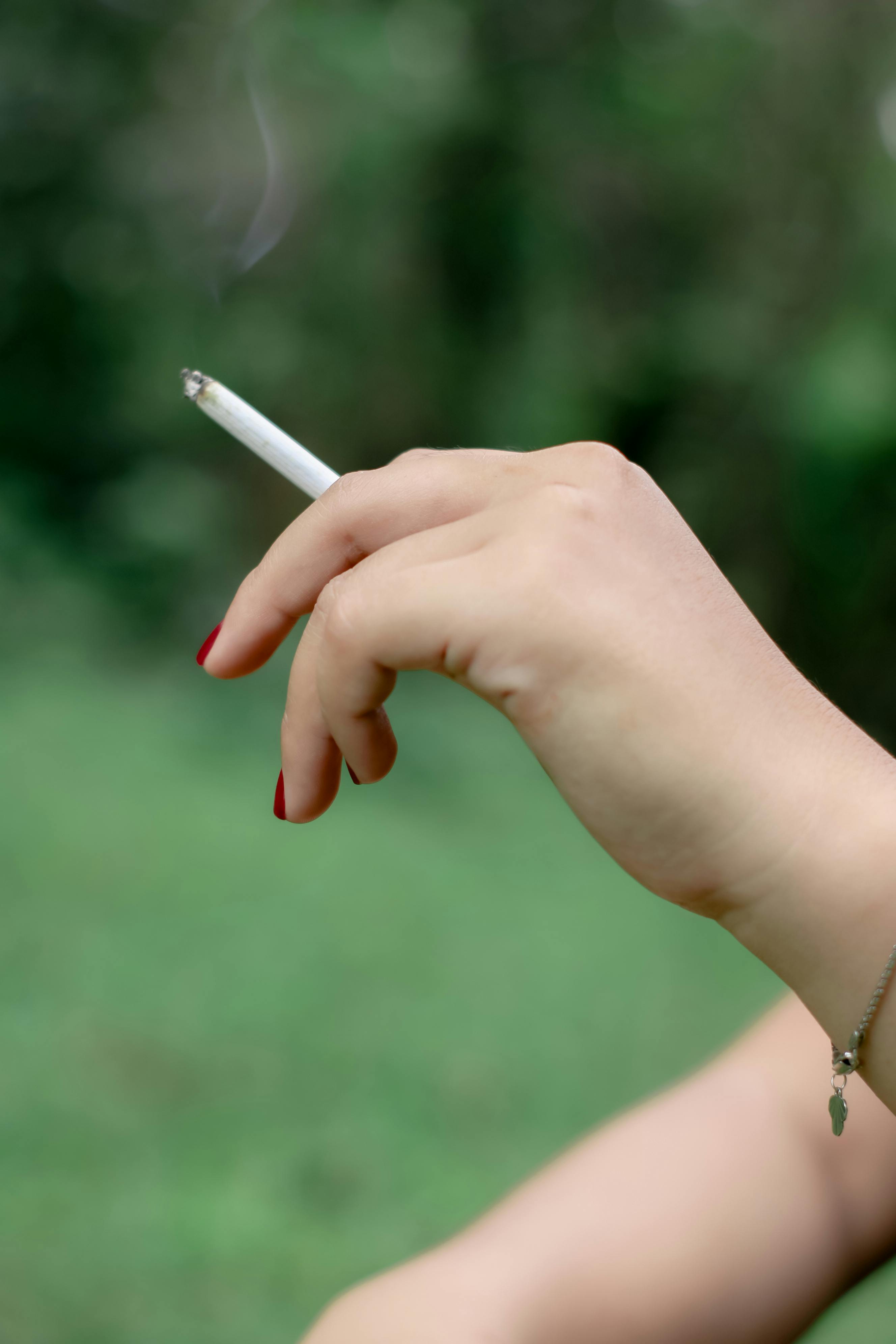 a person holding a cigarette stick