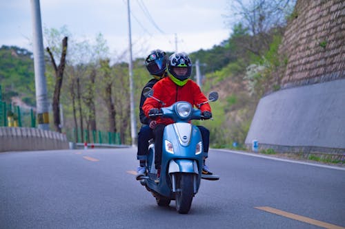 Men in Helmets Riding Blue Motorcycle on Road