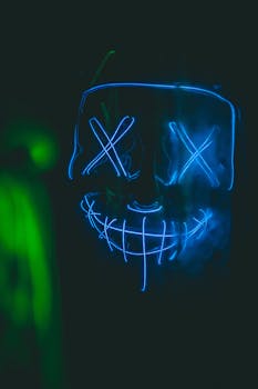 Vibrant neon mask art glowing in blue and green light, creating a surreal and mysterious atmosphere.