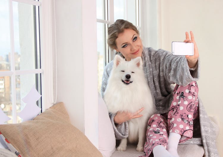 Woman Taking A Photo Of Herself With White Dog