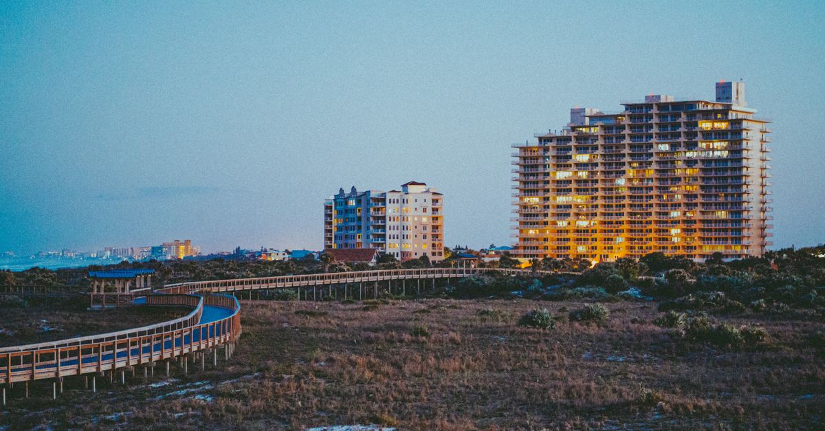 Scenic view of urban buildings illuminated at dusk with a boardwalk leading through a grass field.