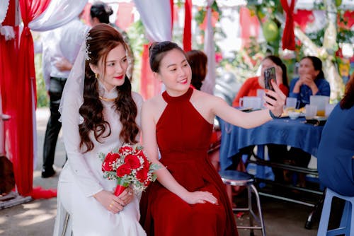 A Woman in Red Dress Taking Selfie with the Bride