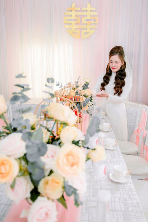 Free A beautiful bride in wedding dress adjusts decor at an elegant table setting. Stock Photo