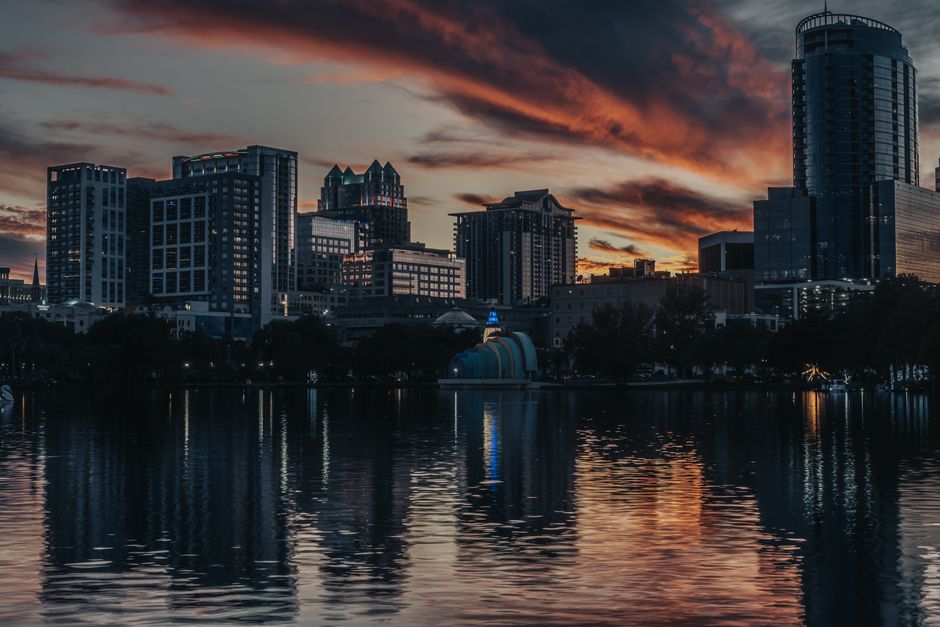 Breathtaking view of Orlando's skyline illuminated at dusk, reflecting on the calm lake surface.