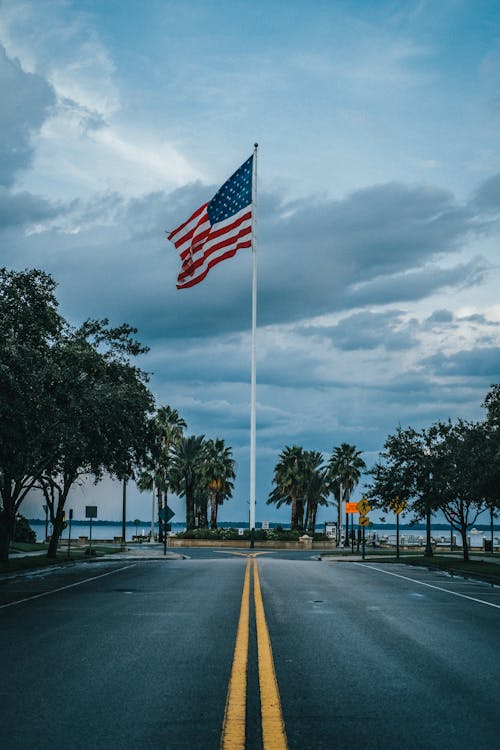 Us Flag on a Pole standing Between the Road