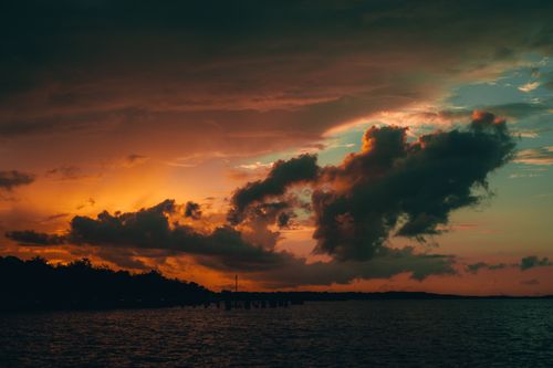 Free Captivating sunset over ocean with vibrant clouds creating dramatic atmosphere. Stock Photo
