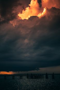 A dramatic cloudy sky with vibrant colors above a calm ocean during the evening.