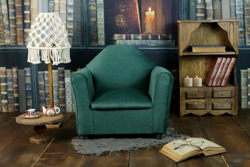 Green Sofa Chair Beside Brown Wooden Table with Lamp and Bookshelf