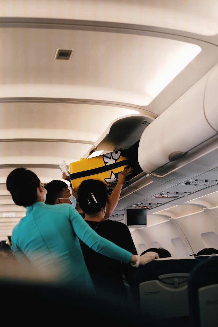 Passengers Putting Their Luggage Inside The Overhead Bin 