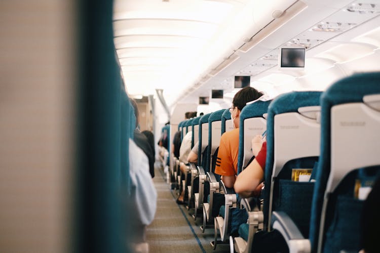 People Sitting On Blue Seats Inside An Airplane