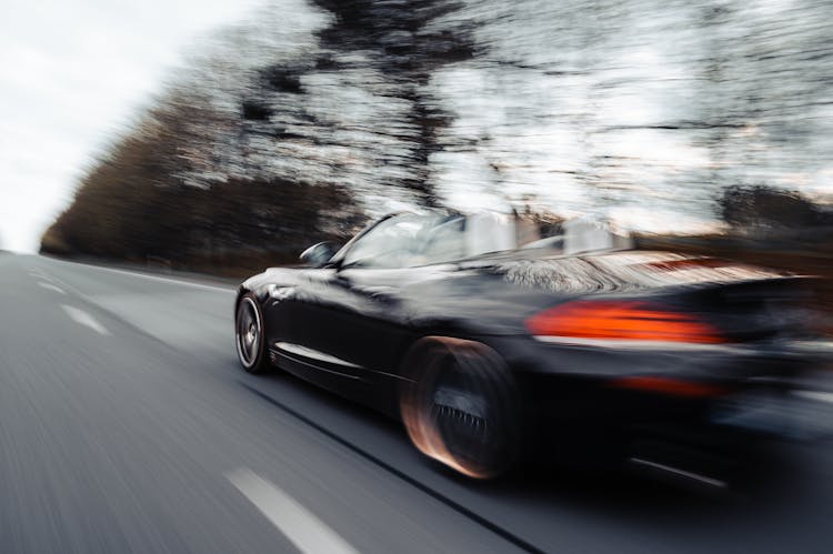 Speeding Black Car On An Asphalt Road