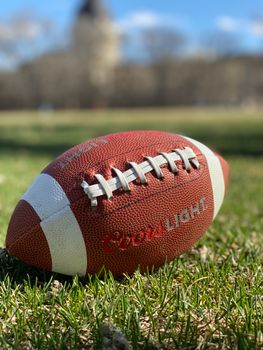 A close-up of a leather football on a sports field in Canada during daytime.