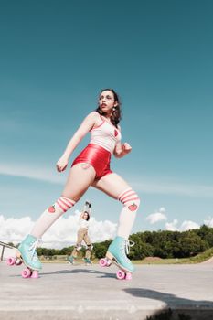Two women enjoying roller skating at an outdoor skate park on a sunny day.