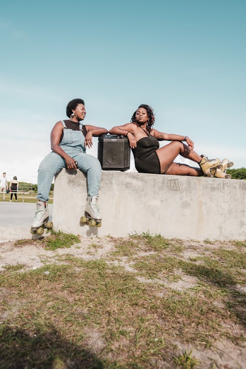 Women Sitting Together While Leaning on a Speaker